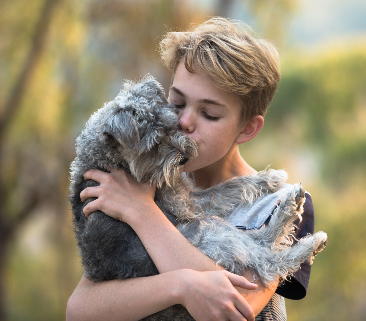 A young boy holding a dog while outside